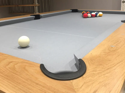 Close up of corner section of Manhatten 7ft Pool Table. Wooden top rail with metallic body and legs. Light slate cloth.
